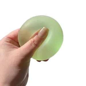 Translucent green maltose stress relief squishy ball toy being squeezed by a human hand