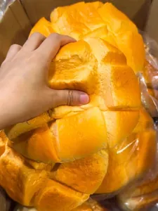 Primo piano di una mano che schiaccia un maxi squishy a forma di panino all'ananas nel cartone