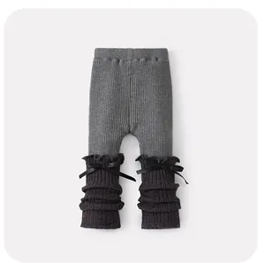 Détail de legging en maille pour bébé avec volants et nœuds noirs en couleur grise