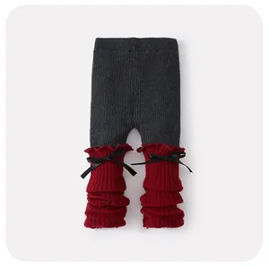 Détail de legging bébé côtelé gris et rouge avec des nœuds noirs