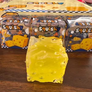 Detailweergave van een geel kaas-squishy-speeltje met de winkelverpakking erbij.