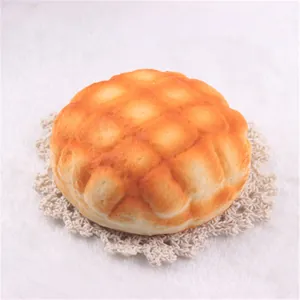 Detail of a realistic slow-rising pineapple bun squishy toy on a white lace coaster