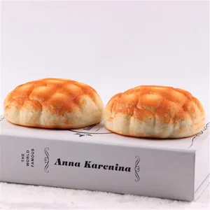 Close-up of two realistic squishy pineapple bun toys on a white decorative book