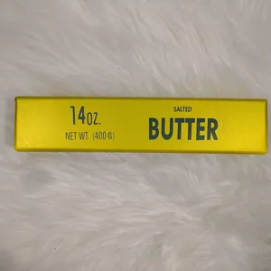 Jouet squishy relaxant en forme de bâton de beurre jaune sur fond de fourrure blanche