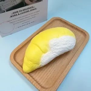 Realistic yellow banana cake food squishy toy for stress relief shown on a wooden tray