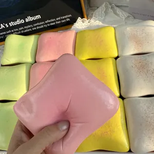 Detailed view of a hand squeezing a colorful slow rising butter toast squishy toy