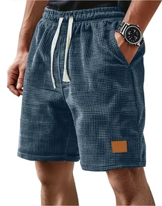 Close-up view of men's blue waffle knit casual shorts with white drawstring and patch detail