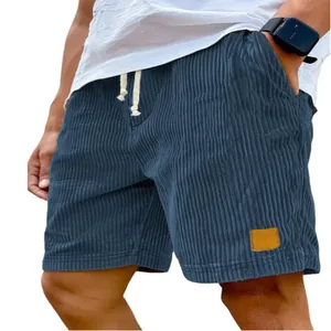 Detailweergave van de blauwe corduroy herenshort met trekkoord en vintage logo-patch.
