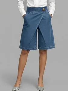 Close-up of blue asymmetric denim-style culottes featuring a decorative gold button.