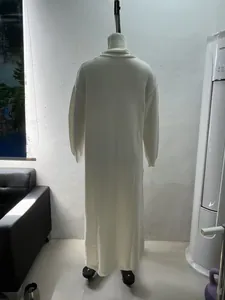 Detailed back view of a white turtleneck knitted maxi dress on a mannequin in a studio