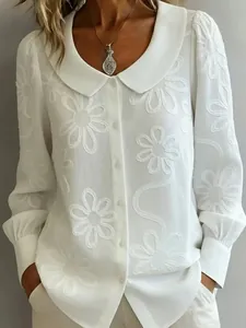 Détail d'une chemise blanche à manches longues avec broderie florale et col Claudine chic