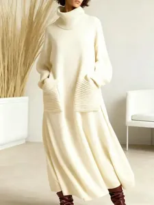 Detail shot of a cream-colored turtleneck knit maxi dress featuring cozy ribbed patch pockets