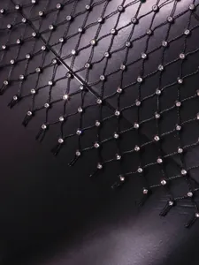 Close-up detail of black fishnet fabric with sparkling rhinestones for women.