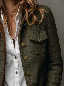 Detailed view of dark green herringbone tweed blazer featuring velvet trim and gold buttons