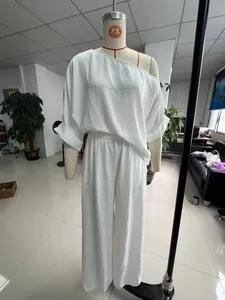 Elegante set coordinato bianco con top con spalla scoperta e pantaloni a gamba larga per donna.