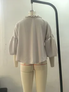 Vue arrière d'un élégant chemisier beige avec col volanté et manches bouffantes