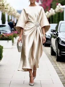 Elegante vestido de satén champán con detalle de flor de cristal en la cintura.