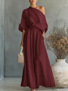 Elegante set bordeaux con top monospalla e pantaloni larghi in un ambiente minimalista