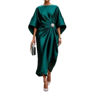 Elegante vestido de satén verde oscuro con broche de flor y mangas de murciélago