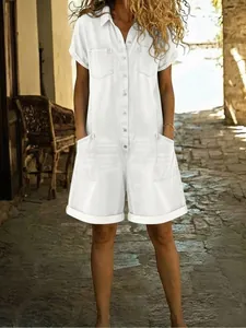 Woman wearing a casual white short-sleeve denim romper with pockets in a scenic alley