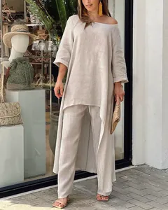 Ensemble deux pièces en lin beige élégant avec haut asymétrique à manches longues et pantalon.