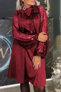 Dettaglio dell'abito corto bordeaux con maniche di paillettes e fiocco al collo.