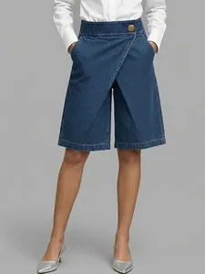 Detail view of women's asymmetrical high-waisted denim-look shorts on model
