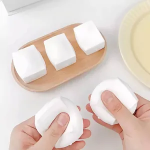 White tofu-shaped squishy toy for stress relief being squeezed by person's hands.