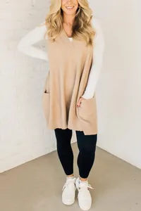 Stilvolle beige Strickweste mit V-Ausschnitt und Taschen über weißem Langarmshirt