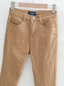 Dettaglio dei jeans a zampa vintage color cammello a vita alta appesi a una gruccia.