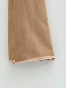 Dettaglio dell'orlo sfrangiato a vivo di un jeans svasato elasticizzato marrone vintage