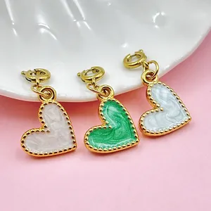 Primer plano de tres colgantes de corazón en blanco y verde para joyería de bricolaje.