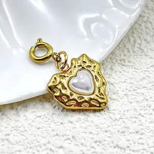 Primer plano de un dije de corazón martillado dorado con incrustación de perla