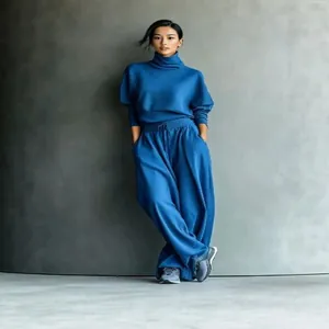 Vista de cuerpo completo de conjunto azul de mujer con cuello alto y pantalones anchos