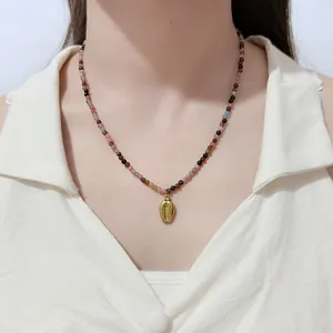Detail einer bunten Naturstein-Perlenkette mit goldenem Muschel-Anhänger.