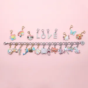 Primo piano di ciondoli colorati a forma di unicorno e bracciale su sfondo rosa.