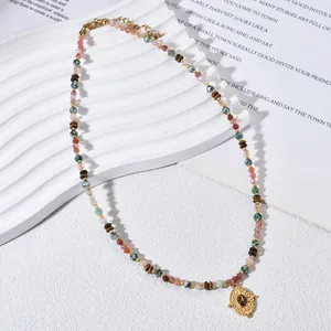 Detailaufnahme einer bunten Naturstein-Perlenkette mit elegantem goldenem Ovalanhänger