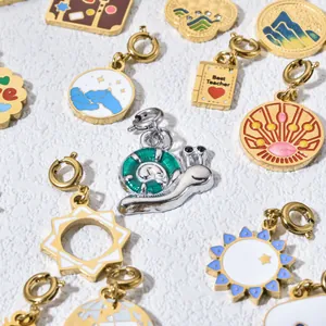 Close-up of various gold-plated enamel charms featuring snail sun and tarot motifs