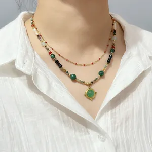 Detailed close-up of vintage agate and tiger eye beaded necklace with green pendant