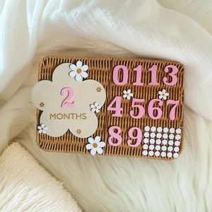 Houten baby mijlpaal set met bloemenkaart en roze cijfers op een rotan mandje voor baby.