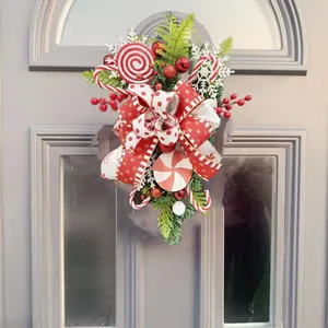 Vista detallada de una corona de dulces navideños con lazos rojos decorando una puerta.