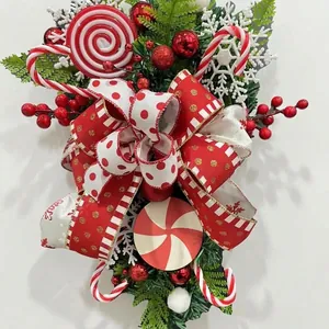 Feestelijke rood-witte kerstkrans in de vorm van een zuurstok met lolly's en linten.
