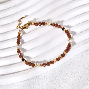 Macro detail of the brown goldstone beads and gold-tone spacers on a white wave tray