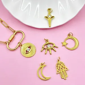 Detailweergave van vergulde DIY-sieradenhangers met boze oog-, maan- en hamsa-ontwerpen