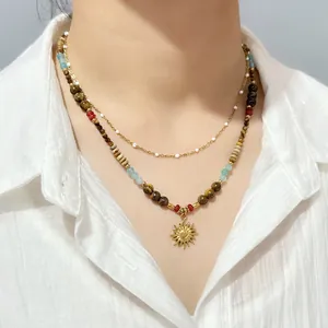 Macro detail of vintage beaded necklace with natural tiger eye and golden sun pendant