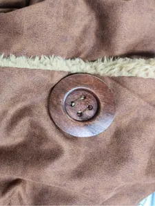Gros plan d'un bouton en bois vintage sur un manteau d'hiver marron en daim pour femme.