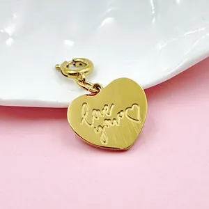 Primer plano de un dije de corazón de acero inoxidable dorado grabado con 'love you'