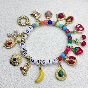 Detail of colorful charm bracelet with 'YOU ARE MAGIC' beads and fruit charms