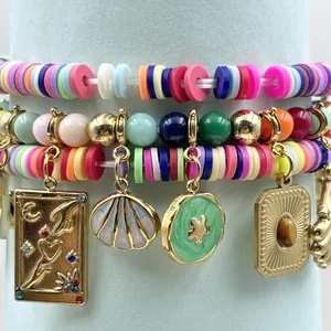 Vista detallada de pulseras de cuentas de arcilla de colores con dijes dorados y concha.