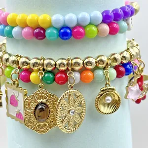 Vista macro detallada de pulseras de cuentas de colores con varios dijes y colgantes dorados